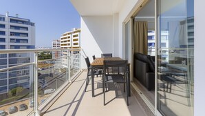 A balcony with a table and chairs, a sofa, and a glass door leading to a living area.
