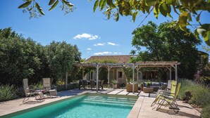 Une piscine avec des chaises longues et un espace patio couvert.