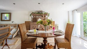 Un coin repas avec une table ronde en bois, des chaises en osier et un vase de fleurs.
