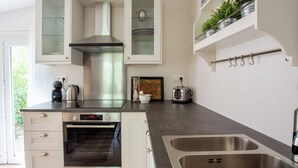 Une cuisine moderne avec des meubles blancs, un évier en acier inoxydable, un four encastré et un grille-pain.