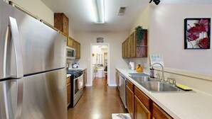 A kitchen with stainless steel appliances, wooden cabinets, a sink, and a countertop.