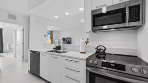 Una cocina moderna con electrodomésticos de acero inoxidable, armarios blancos y horno empotrado.
