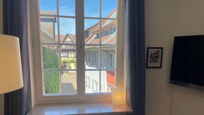Una habitación con ventana que da a un patio, un radiador abajo y un cuadro en la pared.