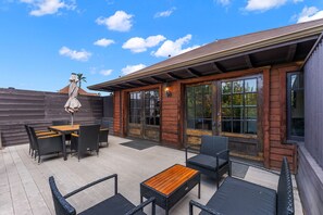 Un patio con mobiliario exterior, una mesa de madera y un área cubierta con una mesa y sillas.