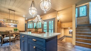 A modern kitchen with a central island, wooden flooring, and large windows. - Multi-Level Getaway | Pool, Hot Tub and Fireplace (Sevierville)