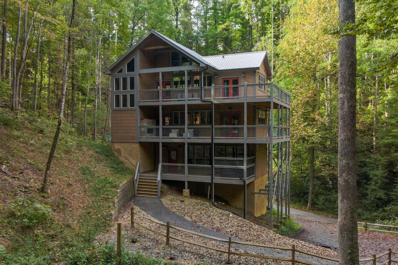 Een meerlaags chalet met een balkon op elke verdieping, omgeven door een bos.