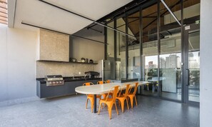 Eine moderne Küche mit integriertem Grill, einem Kühlschrank und einem Essbereich mit orangefarbenen Stühlen.