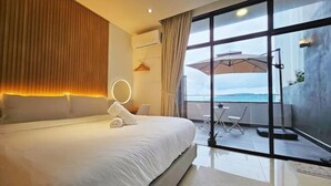 Una habitación de hotel moderna con una cama grande, un balcón con vistas y un espacio bien iluminado.