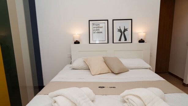 A neatly made bed with two pillows, a bedside lamp, and two framed pictures on the wall. - Casa delle camelie - Two Bedroom Apartment, Sleeps 6 (Naples)