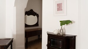 A room with a wooden bench, a mirror, a framed picture, and a cabinet with a plant. - Casa delle camelie - Two Bedroom Apartment, Sleeps 6 (Naples)
