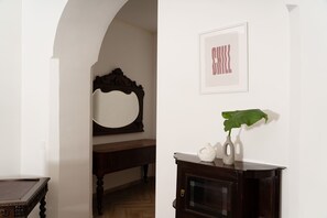 A room with a wooden bench, a mirror, a framed picture, and a cabinet with a plant.