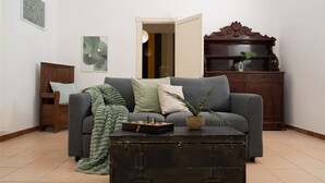 A living room with a sofa, a wooden cabinet, a green blanket, and a suitcase. - Casa delle camelie - Two Bedroom Apartment, Sleeps 6 (Naples)