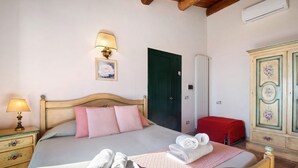 Un dormitorio con cama, mesita de noche con lámpara, cómoda y una puerta.