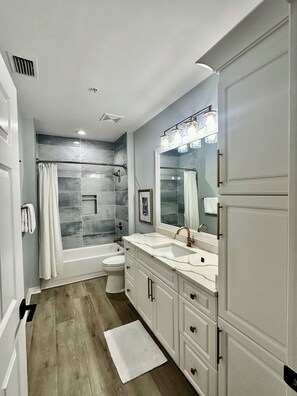 A modern bathroom with a double vanity, a large mirror, a bathtub, and a toilet. - Luxury 2 Bed 2 Bath  Penthouse Bayfront Condo off 5th Avenue (Naples)