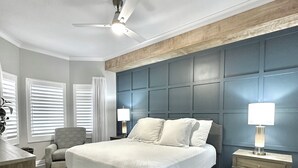 A bedroom with a large bed, a ceiling fan, a nightstand with a lamp, and a chair. - Luxury 2 Bed 2 Bath  Penthouse Bayfront Condo off 5th Avenue (Naples)