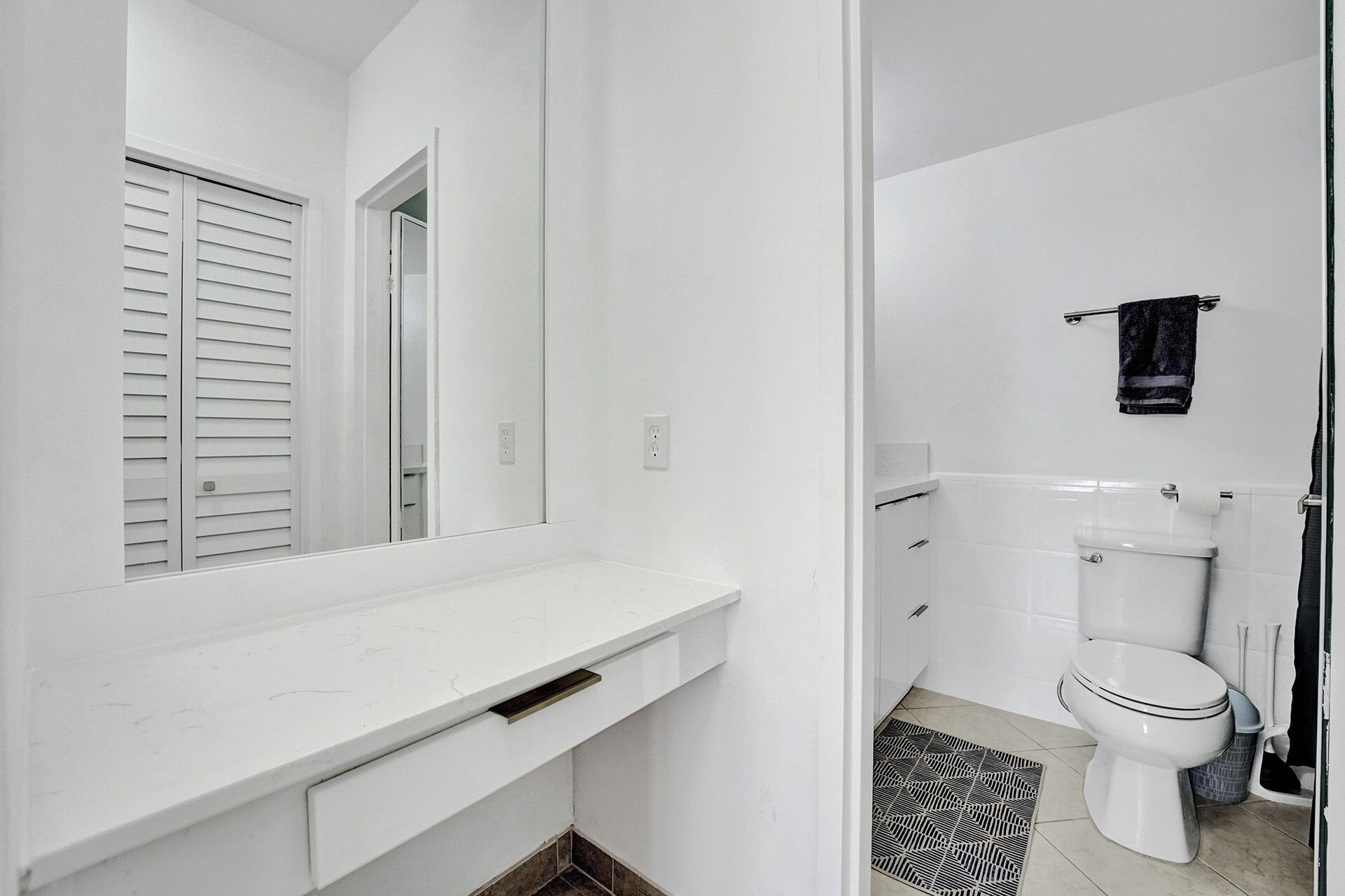 Een badkamer met een wit wastafelmeubel, toilet en douchehoek.