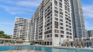 A modern hotel with multiple high-rise buildings, a swimming pool, and outdoor seating areas. - Hallandale Beach - 2 BR Luxury Condo (Hollywood)