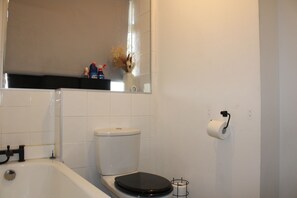 A bathroom with a toilet, a bathtub, and a toilet paper holder. - FREE Parking 2-Bedroom Apartment In The Centre of Wimbledon! (London)