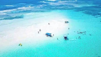 A beach with clear turquoise water, a sandy shore, and several boats.