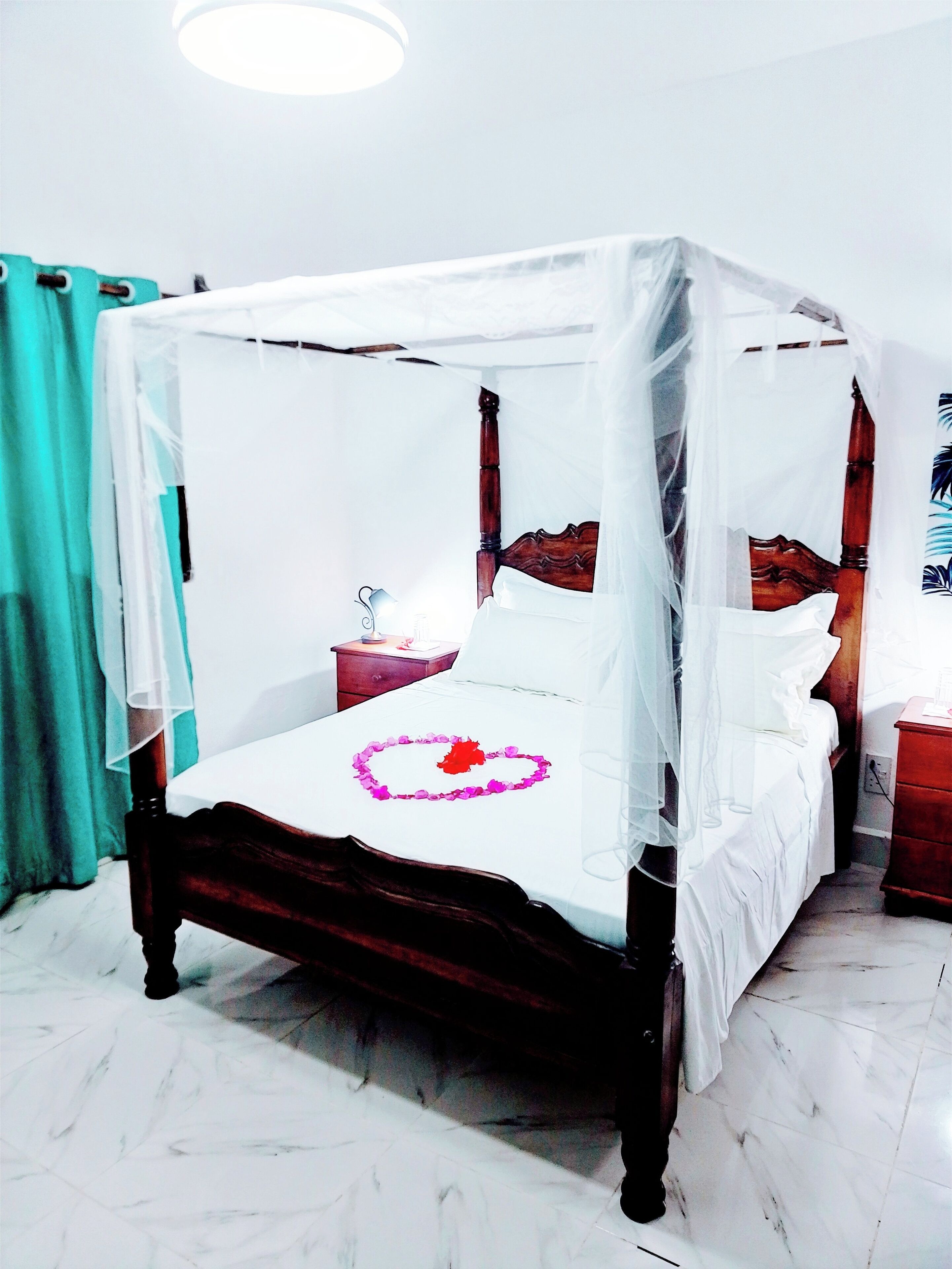 A four-poster bed with a canopy, a bedside table, and a nightstand.