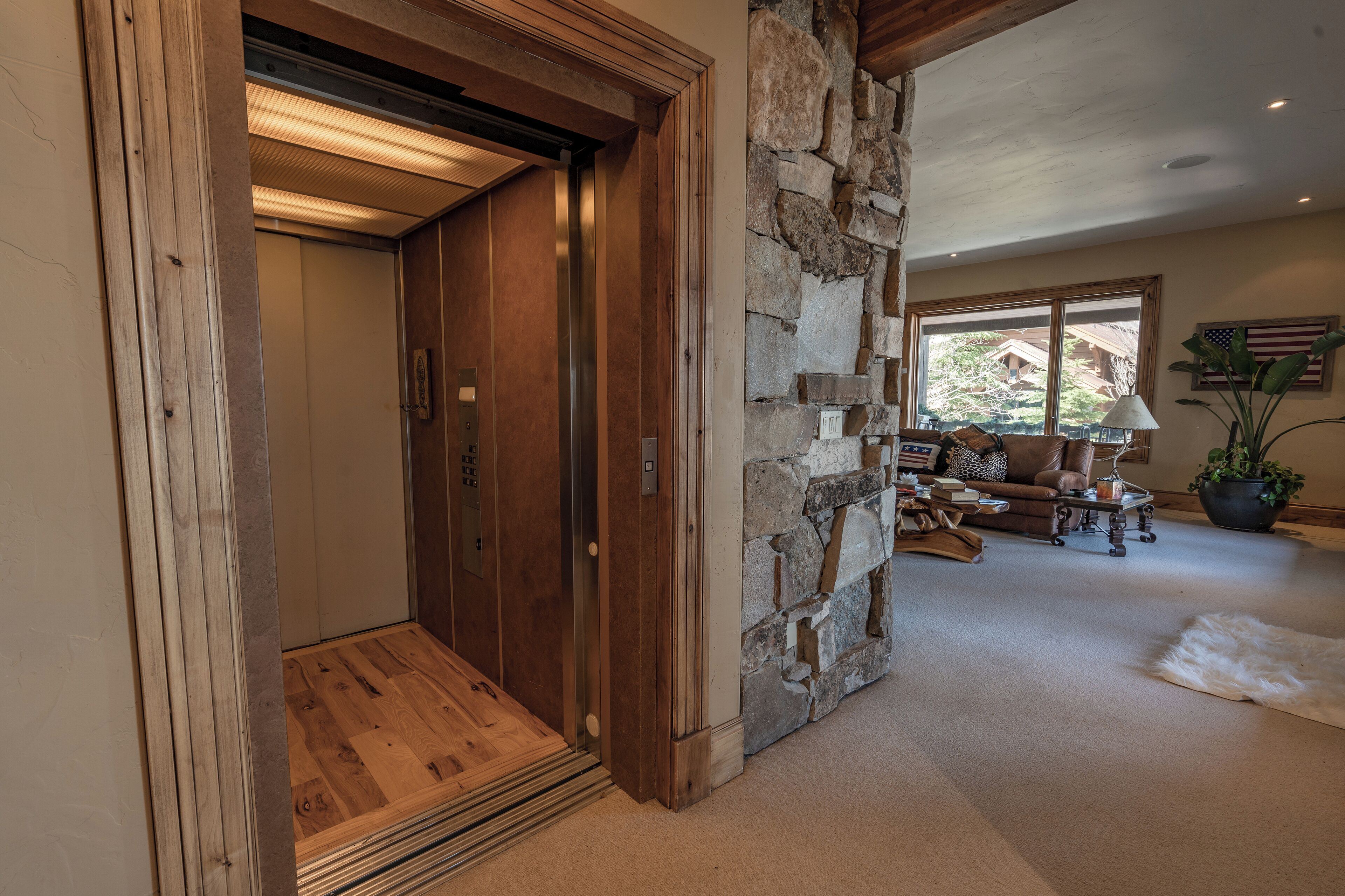 Un intérieur comprenant un ascenseur en bois, un mur en pierre et un espace de vie avec un canapé et une table.