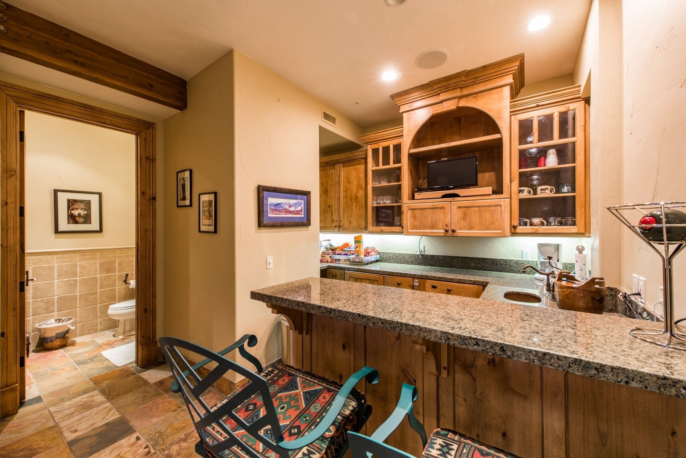 A kitchen with wooden cabinets, a granite countertop, and a built-in TV.