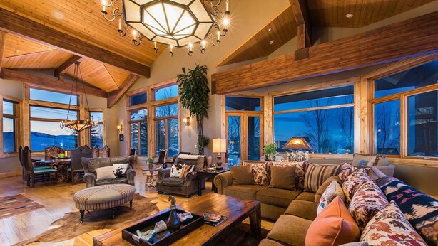 Un salón amplio con un techo de madera grande, una chimenea y vistas a las montañas.