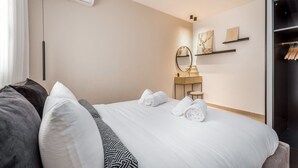 Une chambre d’hôtel comprenant un lit, une table de chevet, un miroir et une armoire.