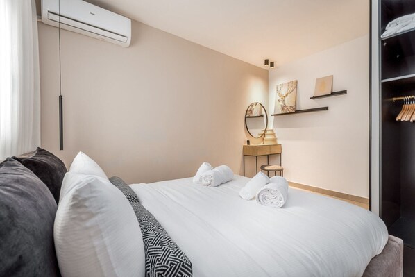Une chambre d’hôtel comprenant un lit, une table de chevet, un miroir et une armoire.