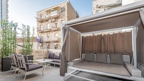 A covered outdoor seating area with a sofa and chairs, a small table, and a pergola structure. - Machane Yehuda 4 - One Bedroom Apartment, Sleeps 4 (Jerusalem)