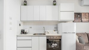 A modern kitchen with white cabinets, a stainless steel sink, a built-in oven, and a white refrigerator. - Machane Yehuda 6 - One Bedroom Apartment, Sleeps 4 (Jerusalem)