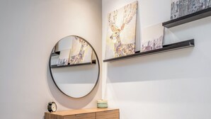 A modern bathroom with a round mirror, wooden vanity, and a small stool. - Machane Yehuda 8 - One Bedroom Apartment, Sleeps 4 (Jerusalem)