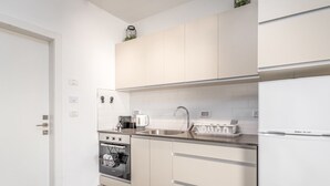 A compact kitchen with white cabinets, a stainless steel sink, a white refrigerator, and a built-in oven. - Machane Yehuda 8 - One Bedroom Apartment, Sleeps 4 (Jerusalem)