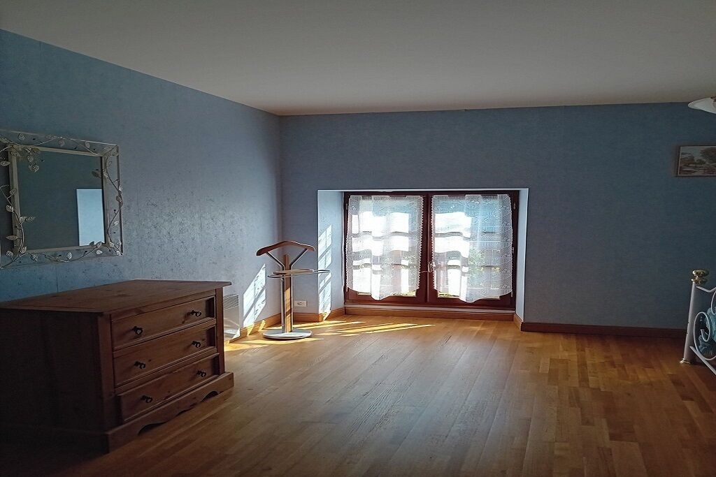 Une pièce comprenant une commode en bois, une chaise en métal et une grande fenêtre donnant sur un immeuble.