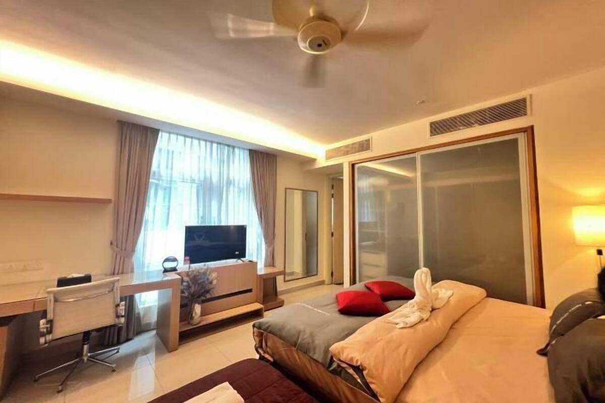 Een hotelkamer met een bed, een bureau, een stoel, een televisie en een schuifdeur.