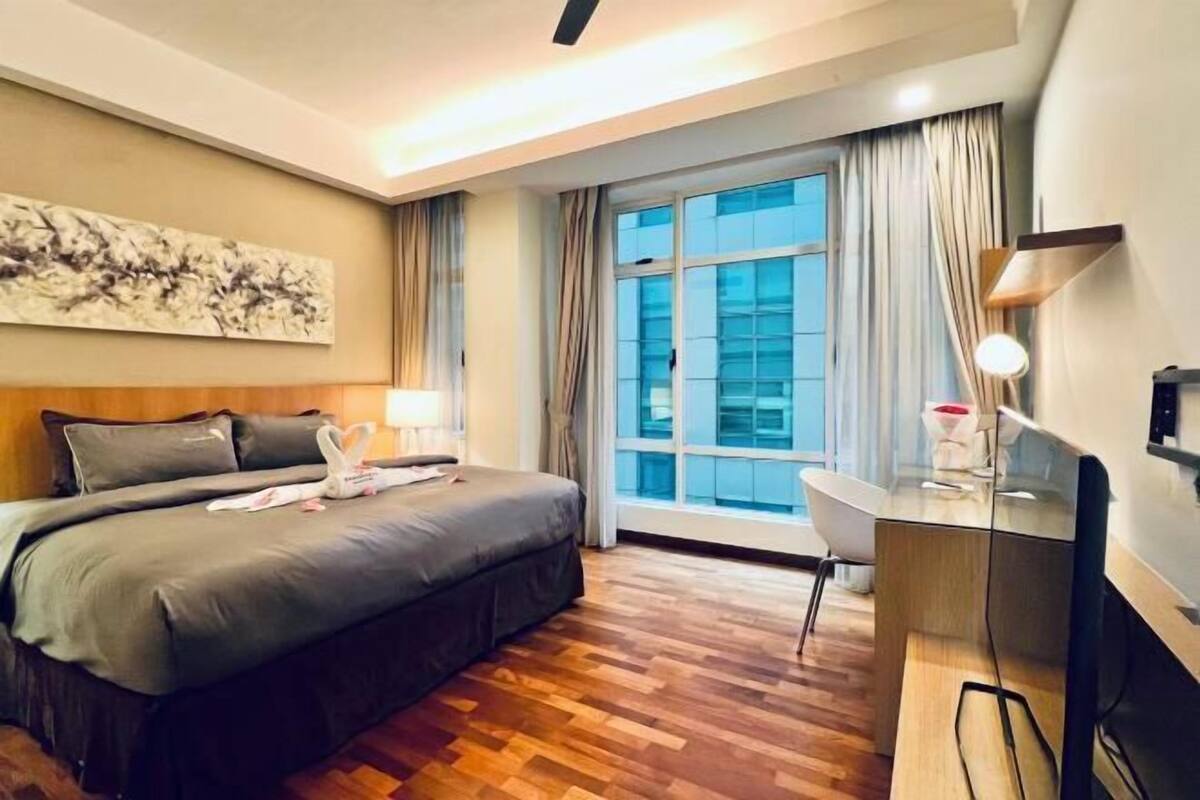 Hotelkamer met een groot bed, een bureau, een stoel, een televisie en een raam met gordijnen.