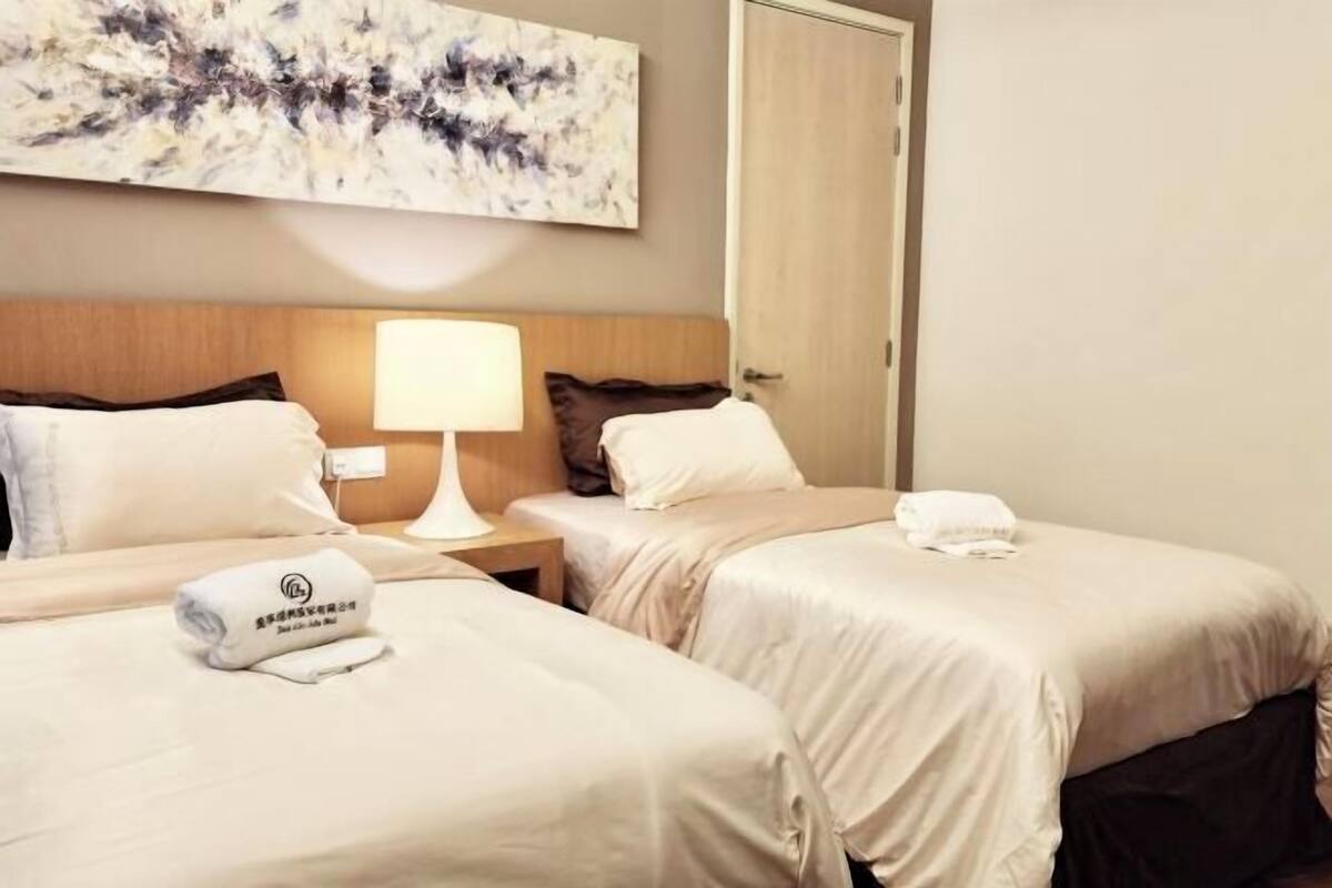 Een hotelkamer met twee bedden, een nachtkastje met lamp, een schilderij aan de muur en een deur.