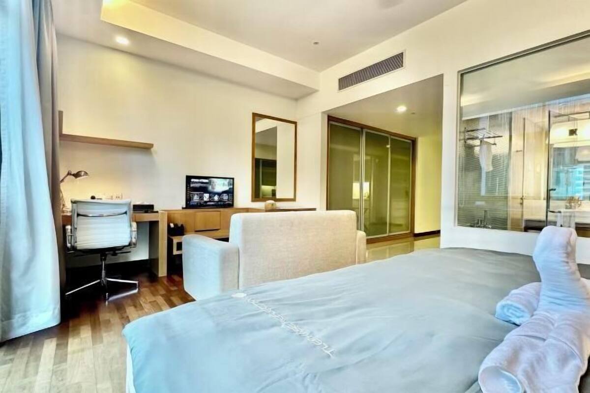 Een hotelkamer met een bed, een bureau met een computer, een stoel en een groot raam.