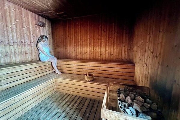 A sauna with wooden benches, a basket, and a stack of firewood. - Lot 163 By ZenGlo (Kuala Lumpur)