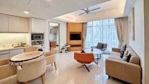 Een moderne woonkamer met een bank, fauteuil, eettafel en een televisie.