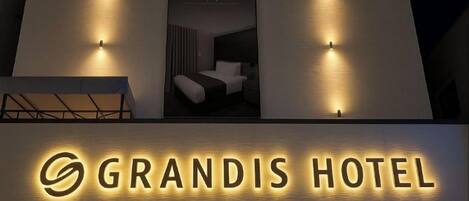 The exterior of the Grandis Hotel with a prominent illuminated sign.