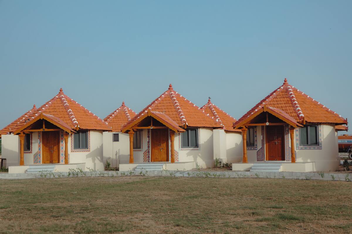 A row of four identical buildings with orange tiled roofs and white walls, each with a wooden door and windows.