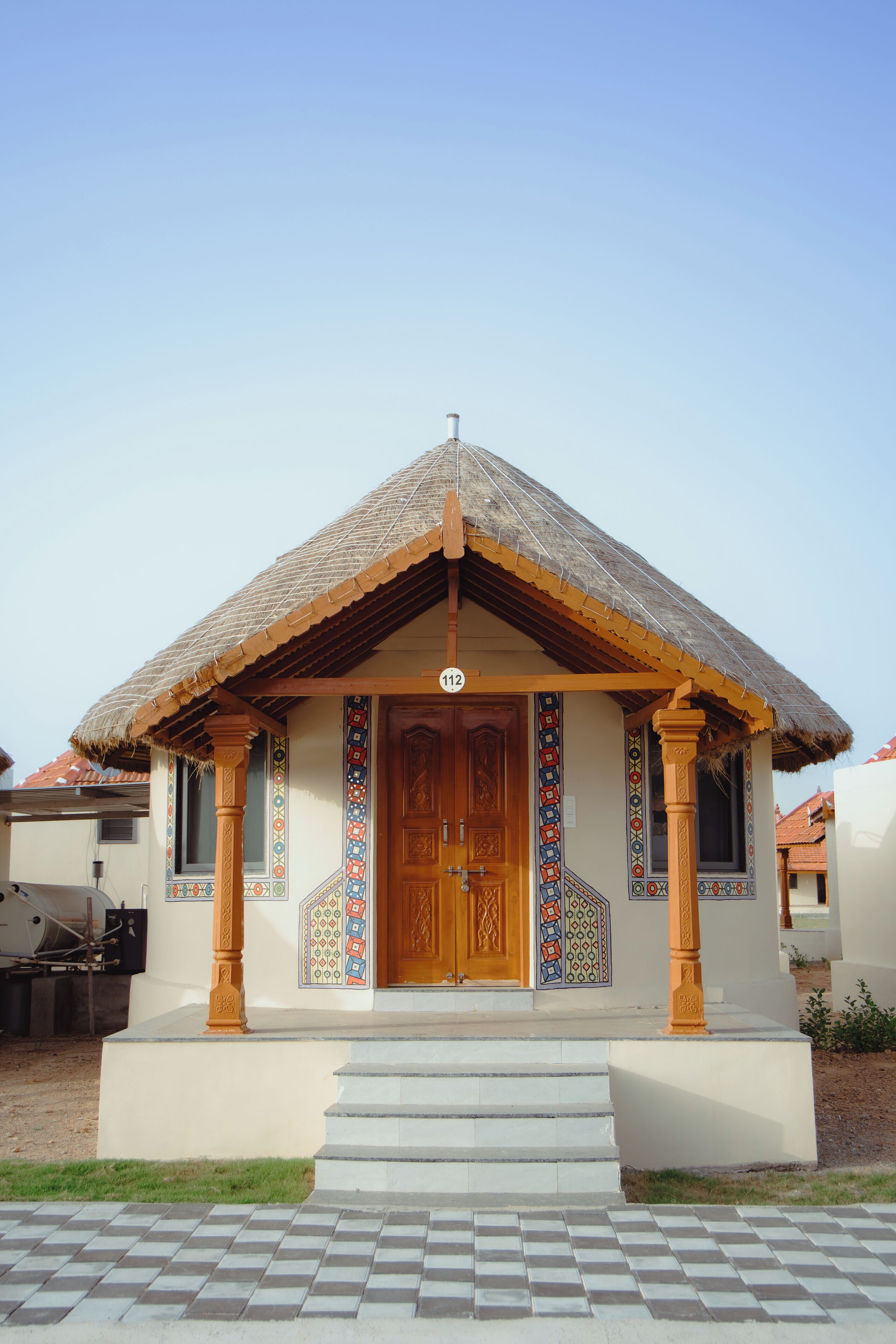 Una casa tradicional con techo de tejas, puerta de madera y diseños coloridos en las paredes.