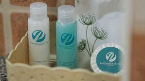 Un ensemble de produits de soins pour la peau présenté dans un panier, avec un logo, un emballage blanc orné d’un motif floral et un petit récipient rond portant également un logo.