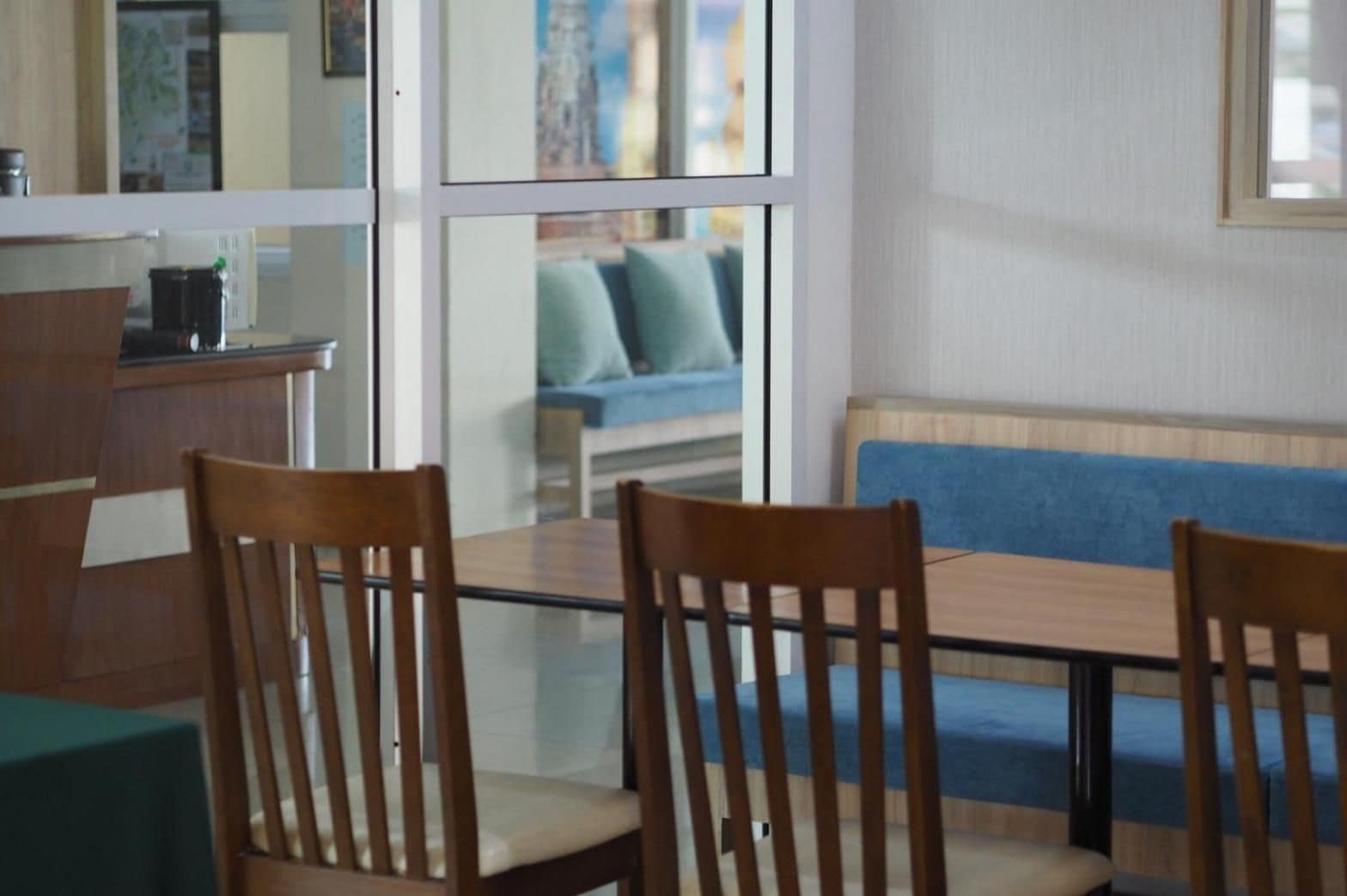 A dining area with a glass table, wooden chairs, and a blue sofa in the background.