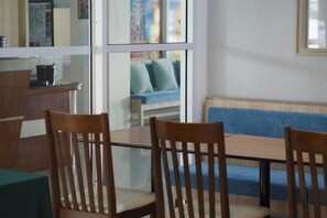 Un comedor con una mesa de vidrio, sillas de madera y un sofá azul al fondo.