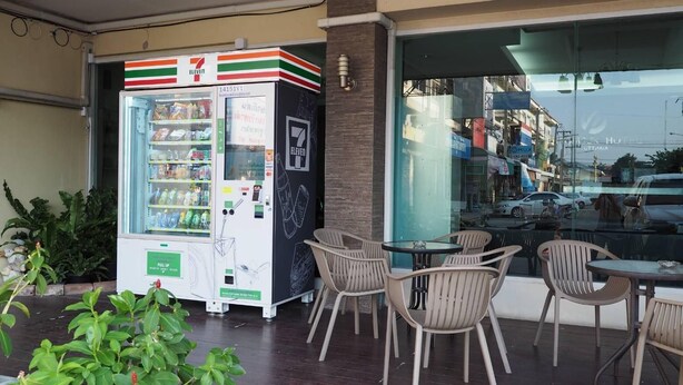 A 7-Eleven convenience store with a vending machine and outdoor seating area. - Phromsuk Hotel Ayutthaya (Phra Nakhon Si Ayutthaya)