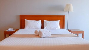 A neatly made bed with white linens, two pillows, and a rolled towel on the bed. - Phromsuk Hotel Ayutthaya (Phra Nakhon Si Ayutthaya)