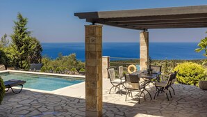 A pool area with a view of the sea, stone flooring, and outdoor furniture. - Melanthi - Three Bedroom Villa, Sleeps 6 (Fiskardo)