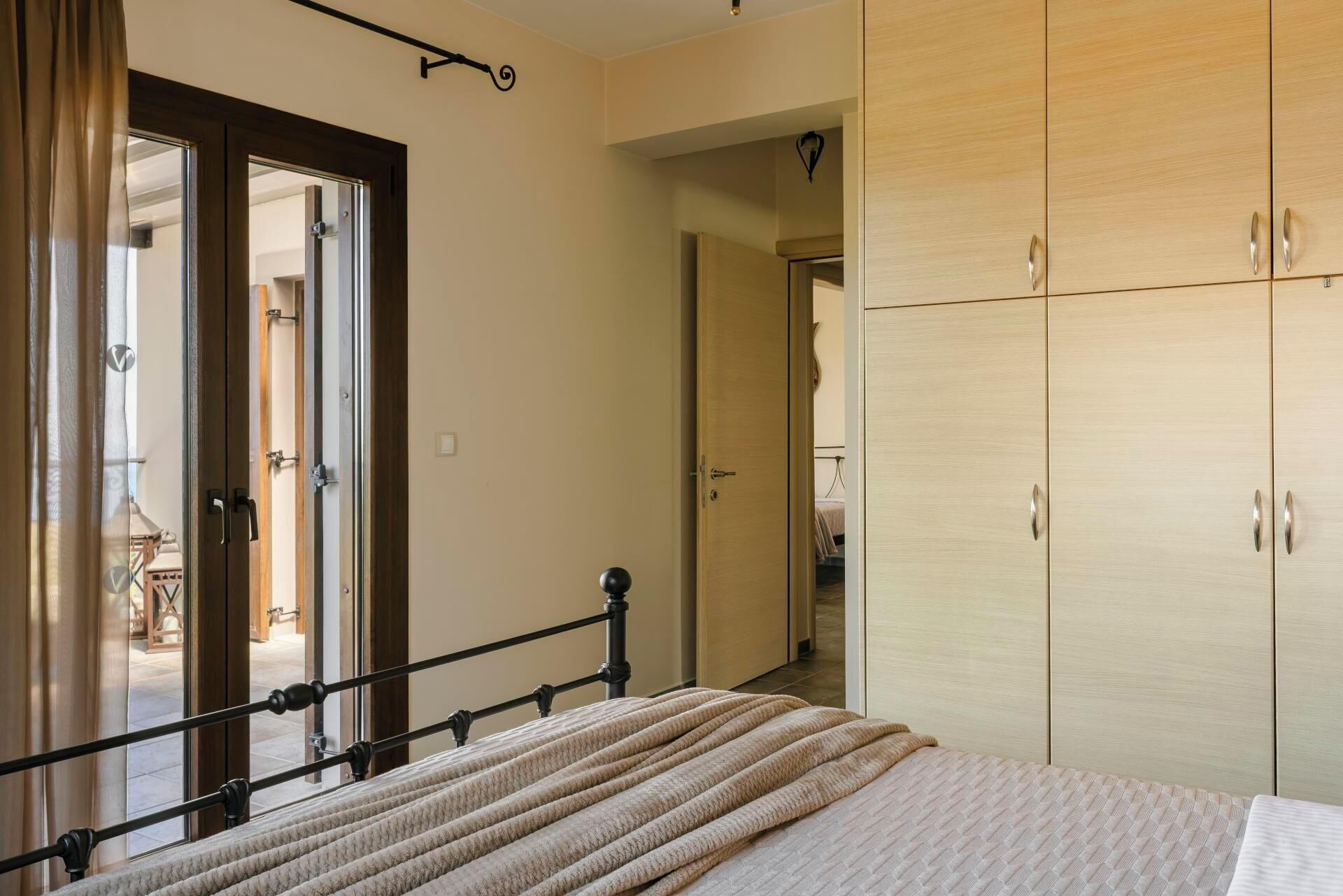 Une chambre à coucher comprenant un lit, une armoire et une porte donnant sur une autre pièce.